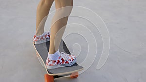 Attractive Asian woman with safety skateboarding knee pad skating at skateboard park .
