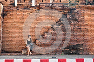 Attractive asian woman sitting on brick wall stairs in Tha Phae Gate at Chiang Mai