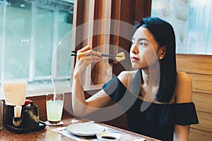 Attractive Asian woman sitting and eating Japanese food alone in the restaurant.