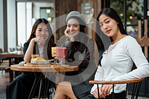 An attractive Asian woman in trendy clothes sitting at a table in a restaurant with her friends