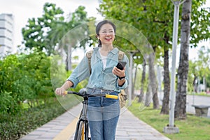 Attractive Asian woman using smartphone in park. She is on her way to work