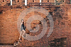 Attractive asian woman walking up the brick wall stairs in Tha Phae Gate at Chiang Mai