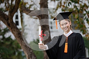 Attractive Asian Women Student Graduate in cap and gown celebrating with certificate in hand and so proud happiness in Commencemen