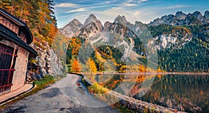 Attractive autumn view of Gosausee Vorderer lake with asphalt walkway road.