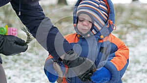 Attractive baby playing in the winter woods with her mother. On the ground, a bit of snow. Boy playing with sabers and