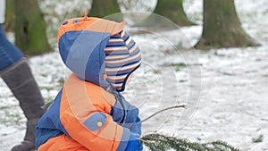 Attractive baby playing in the winter woods with her mother. On the ground, a bit of snow. Boy playing with sabers and