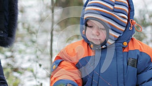 Attractive baby playing in the winter woods with her mother. On the ground, a bit of snow. Boy playing with sabers and