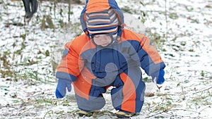 Attractive baby playing in the winter woods with her mother. On the ground, a bit of snow. Boy playing with sabers and