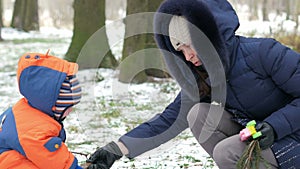 Attractive baby playing in the winter woods with her mother. On the ground, a bit of snow. Boy playing with sabers and