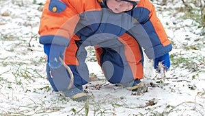 Attractive baby playing in the winter woods with her mother. On the ground, a bit of snow. Boy playing with sabers and