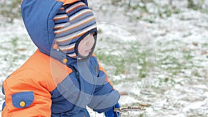 Attractive baby playing in the winter woods with her mother. On the ground, a bit of snow. Boy playing with sabers and