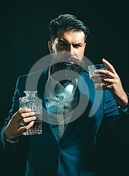 Attractive Bartender in whiskey bar. Stylish rich man holding a glass of old whisky. Man with beard holds glass brandy.