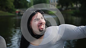 Attractive bearded guy with long hair and fake muscle costume sings outside.