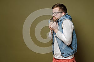 Attractive bearded man wearing glasses is very froze, he takes refuge in bewilderment and perplexity in a vest. Copy