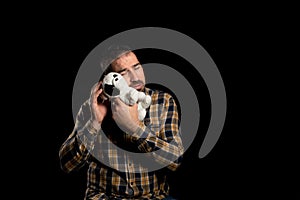 Attractive bearded man in a yellow plaid shirt with a stuffed puppy posing  on black background