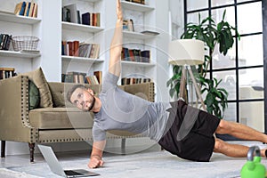 Attractive beared man doing plank exercise at home. Fitness is the key to health