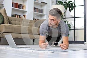 Attractive beared man doing plank exercise at home. Fitness is the key to health