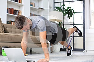 Attractive beared man doing plank exercise at home. Fitness is the key to health