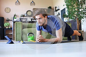 Attractive beared man doing plank exercise at home during quarantine. Fitness is the key to health