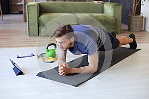 Attractive beared man doing plank exercise at home during quarantine. Fitness is the key to health