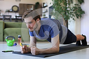 Attractive beared man doing plank exercise at home during quarantine. Fitness is the key to health