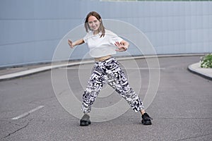 Attractive beautiful caucasian girl is dancing on the street. Sport, dance, urban culture. Fashion lifestyle.