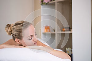 Attractive beautiful girl lying on massage bed in spa salon. Spa aroma therapy and beauty treatments concept.