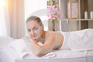 Attractive beautiful girl lying on massage bed in spa salon. Spa aroma therapy and beauty treatments concept