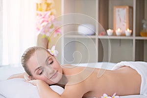 Attractive beautiful girl lying on massage bed in spa salon. Spa aroma therapy and beauty treatments concept