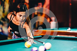 Attractive beautiful girl playing billiard in a club