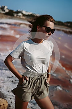 Attractive, beautiful and magnificent young woman with loose brown hair in sunglasses. Countryside landscape, nature. Ashore