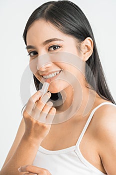attractive beautiful mixed race asian woman applying lipstick on her lips