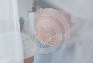 Attractive beautiful pregnant girl stand behind a curtain