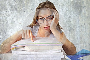 Attractive and beautiful tired student girl leaning on school books pile tired and bored after studying preparing exam looking was