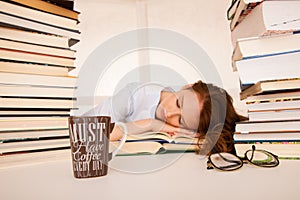 Attractive beautiful tired student sleeps on pile of books with