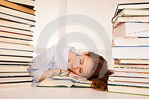 Attractive beautiful tired student sleeps on pile of books