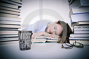 Attractive beautiful tired student sleeps on pile of books with