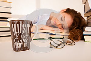 Attractive beautiful tired student sleeps on pile of books with