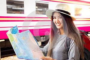 Attractive beautiful traveler woman holding the map and standing at train station. Charming beautiful young woman is planning to