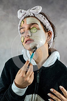 Attractive beautiful woman applying facial clay white mask holding brush