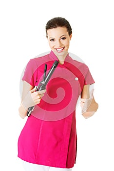 Attractive beautiful woman/beautician holding hair straightener, showing OK.