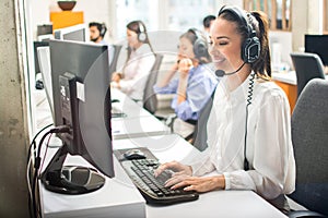 Attractive and beautiful woman customer service operator in headsets at work in office. Business concept