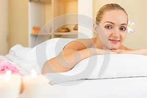 Attractive beautiful woman lay down on bed at spa salon. Beautiful young woman look at camera and get satisfied service of spa