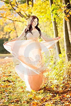 Attractive beautiful woman. Nature, autumn, fall yellow leafs. Fashion orange dress