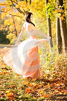 Attractive beautiful woman. Nature, autumn, fall yellow leafs. Fashion orange dress