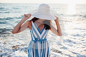 Attractive beautiful woman with white hat on head on sea sunset
