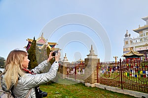 Attractive beautiful young girl holding modern mirror camera on tphotographing a Buddhist temple. Female traveller in old place