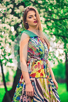 Attractive beautiful young model in colorful dress in summer garden