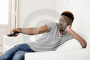 Attractive black african american man sitting at home sofa couch watching television