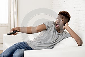 Attractive black african american man sitting at home sofa couch watching television